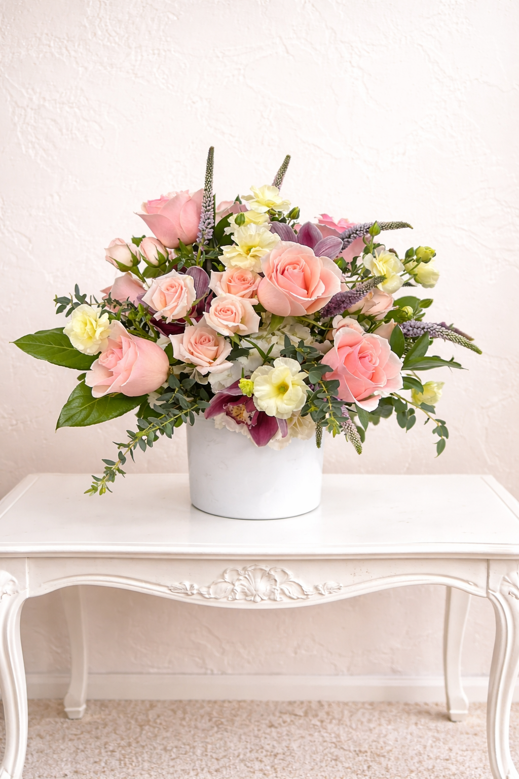 Floral arrangement in a white container on a white table with a light background