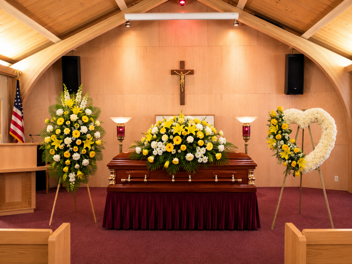 Casket with floral arrangements and candles in a funeral home setting.