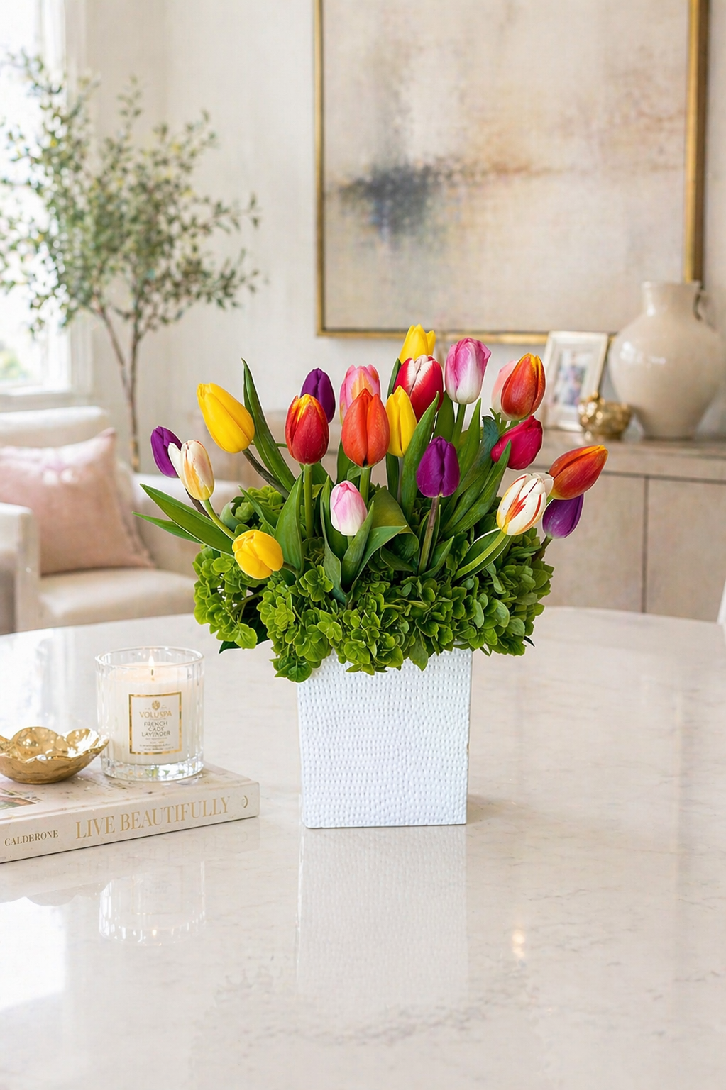 Colorful tulip arrangement in a white vase on a marble table with a neutral background