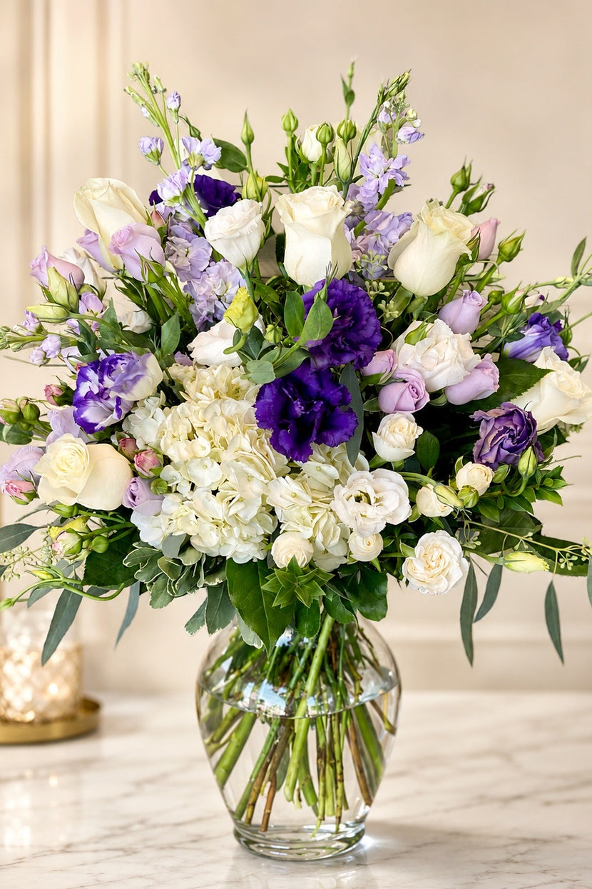 Bouquet of flowers in a clear vase on a marble surface with a neutral background
